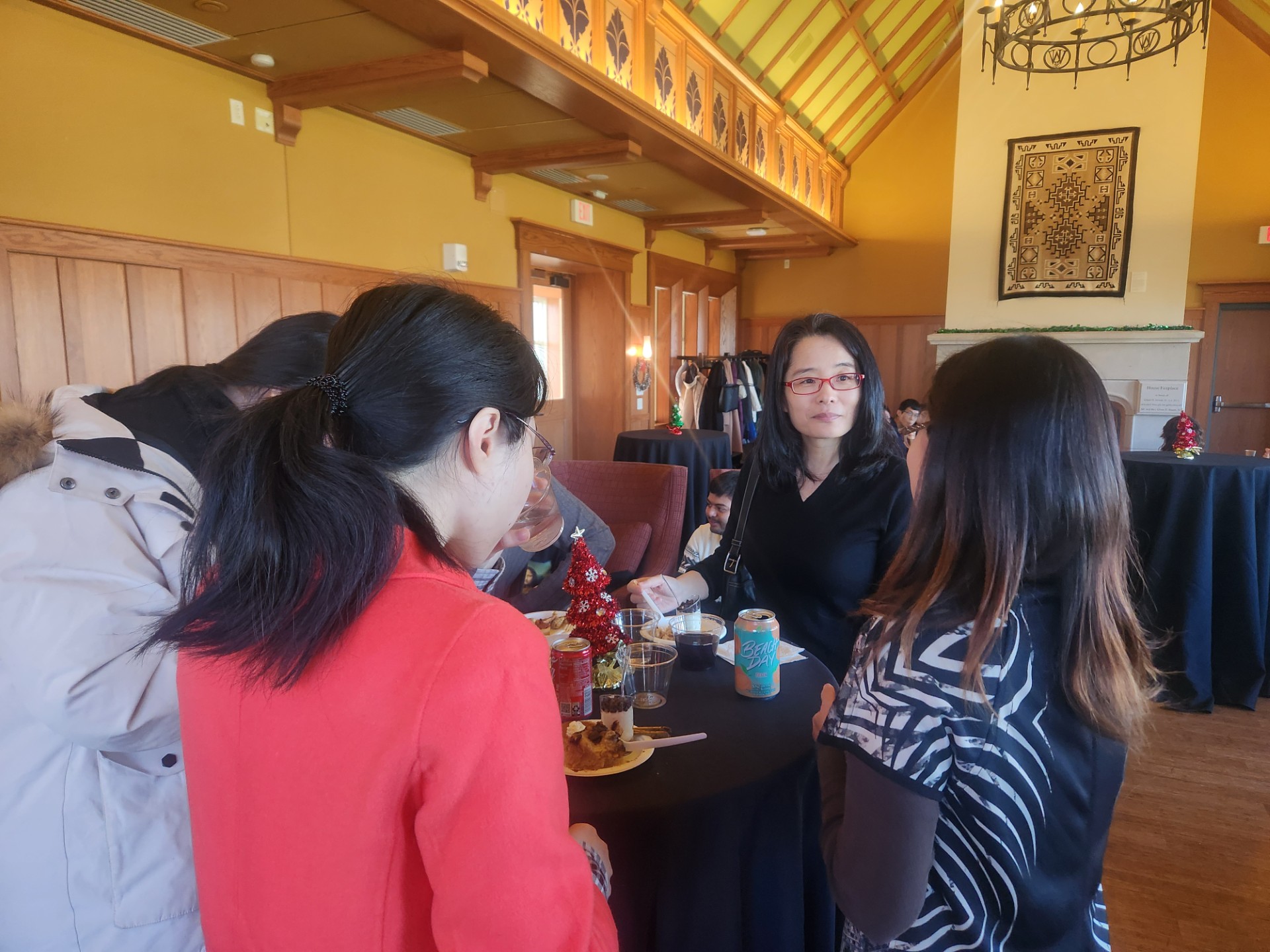 Four people stand around a table, eating and talking