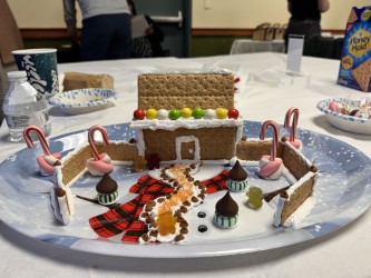 A gingerbread house made of graham crackers and candy sits on a table