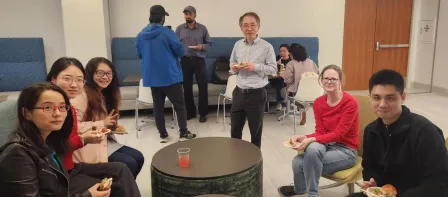 Members of the SDS department and guests sit around a table, talking and smiling